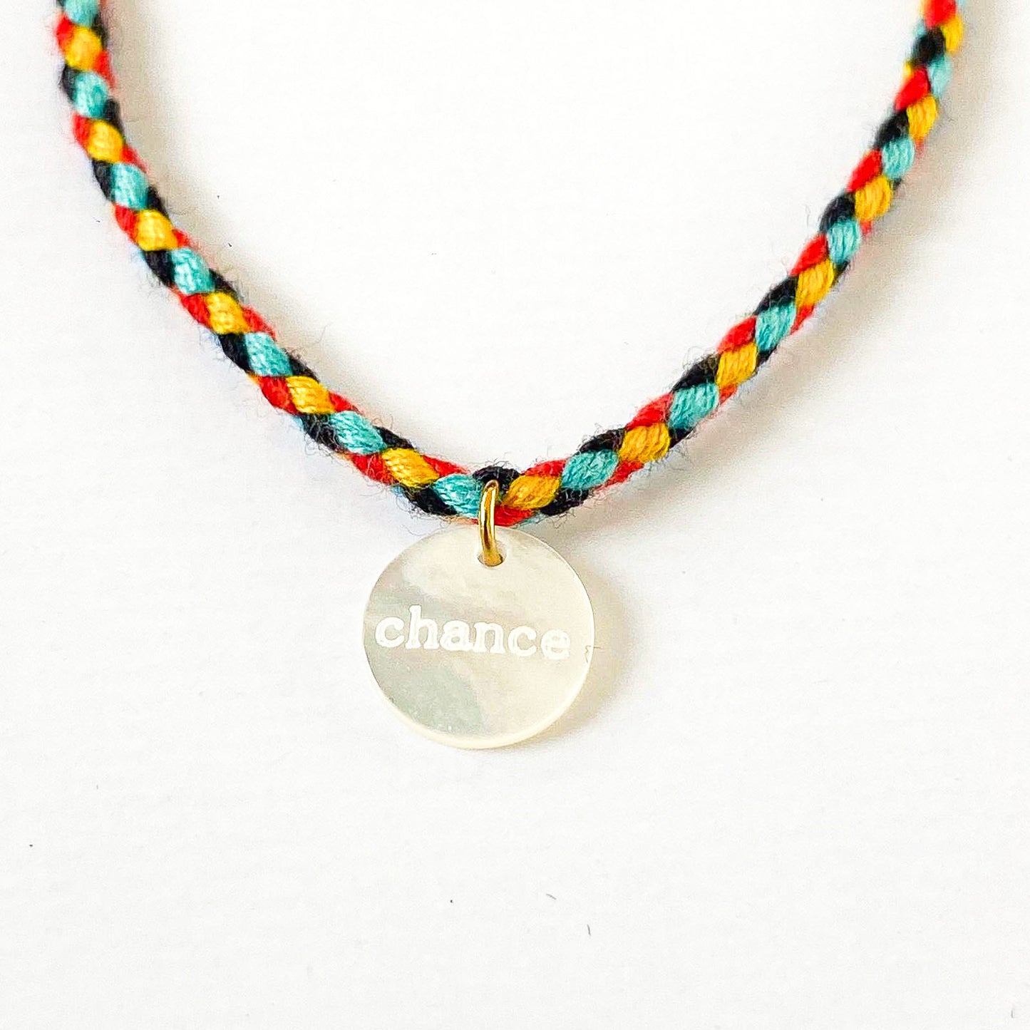 Un bracelet cordon vibrant et multicolore, accentué par un pendentif en nacre arborant le mot "chance". La palette de couleurs évoque la joie et la vivacité, tandis que le pendentif ajoute une touche de délicatesse et de positivité, évoquant l'espoir et les opportunités à saisir. L'ensemble incarne une fusion harmonieuse entre l'esthétique ludique et le symbolisme inspirant.