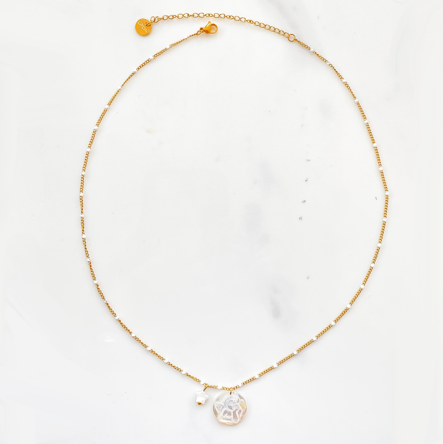 Une composition éblouissante se dévoile : un collier en acier inoxydable captivant, sublimé par un pendentif en nacre blanche délicatement ciselé, représentant l'ange de la Vierge Marie. L'éclat argenté de l'acier contraste harmonieusement avec la douceur nacrée du pendentif, créant une symbiose entre force et grâce, foi et élégance. C'est une pièce qui semble porter en elle une aura de protection et de spiritualité, captivant le regard et l'âme.