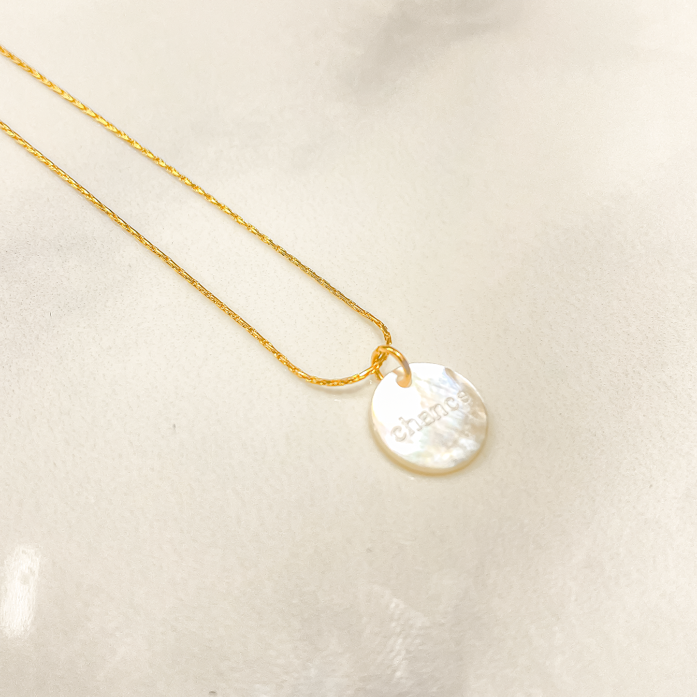 Sur la photo, un collier en acier inoxydable étincelle, orné d'un pendentif délicat. Sur ce dernier, le mot "chance" se détache en nacre, ajoutant une touche d'élégance et de mystère. Présenté dans une boîte soignée, ce bijou incarne à la fois la sophistication et la promesse d'opportunités à venir.