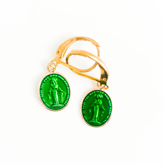 Une paire de boucles d'oreilles pendantes représentant la Vierge Marie, délicatement sculptées en un vert lumineux, évoque une aura de spiritualité et de connexion profonde. Les détails minutieux captent l'essence de la foi et de la grâce, tandis que la teinte verdoyante ajoute une touche de fraîcheur et de renouveau à cette symbolique religieuse intemporelle. Portées avec élégance, ces boucles d'oreilles incarnent la fusion entre la piété et l'esthétique, invitant à la contemplation et à la réflexion.