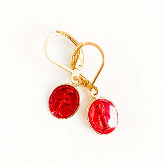 Une paire de boucles d'oreilles en rouge flamboyant, délicatement ornées de l'image de la Vierge Marie, capture l'essence de la foi et de la dévotion. Les nuances vibrantes soulignent la symbolique sacrée, tandis que la finesse des détails évoque une beauté intemporelle. Un mélange envoûtant de couleur et de spiritualité, offrant une expression unique de la croyance religieuse à travers l'art de la parure.