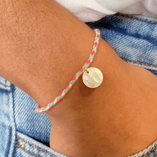 un délicat bracelet cordon rose, orné d'un pendentif en nacre sculpté avec le mot "Love". L'ensemble est présenté dans une élégante boîte assortie, offrant une touche de romantisme et de raffinement à toute occasion.