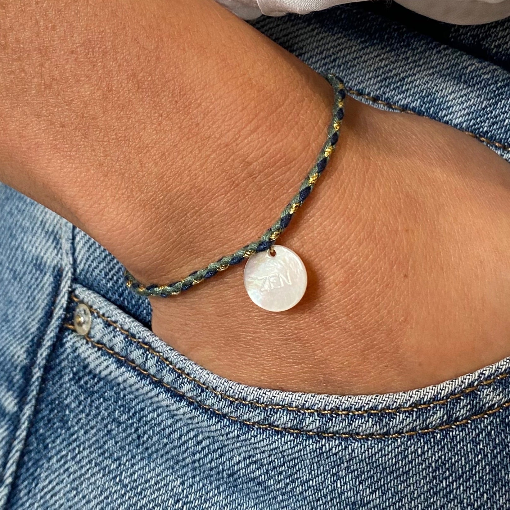 Sur la photo, un bracelet en cordon bleu captivant, orné d'un délicat pendentif en nacre. Le mot "zen" est élégamment inscrit sur le pendentif, évoquant un sentiment de calme et de sérénité. Un accessoire parfait pour ajouter une touche de tranquillité à votre style quotidien.