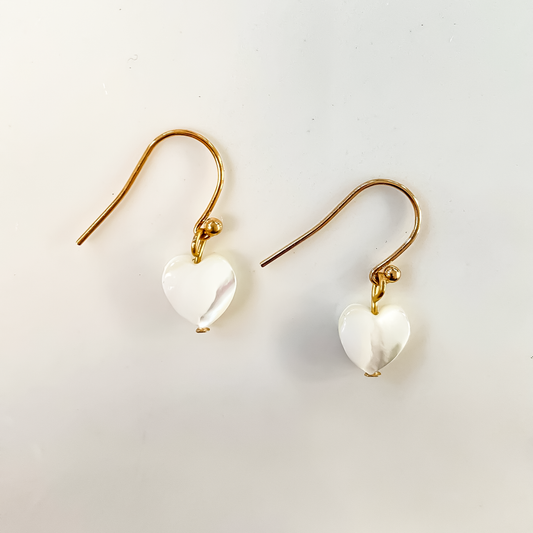 La photo représente des boucles d'oreilles en acier inoxydable muni d'un pendentif cœur en nacre