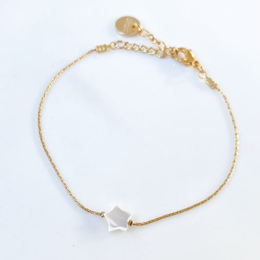 Un bracelet en acier inoxydable, robuste et élégant, entourant délicatement le poignet. Son pendentif en étoile en nacre, dégageant une aura de délicatesse et d'éclat naturel, captivant le regard par sa finesse. Une fusion harmonieuse entre la force de l'acier et la douceur de la nacre, incarnant un style intemporel et raffiné.